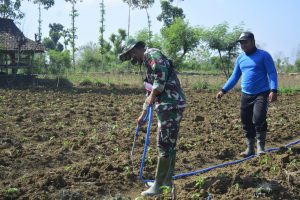 Anggota Satgas TMMD Bantu Petani Sirami Tanaman